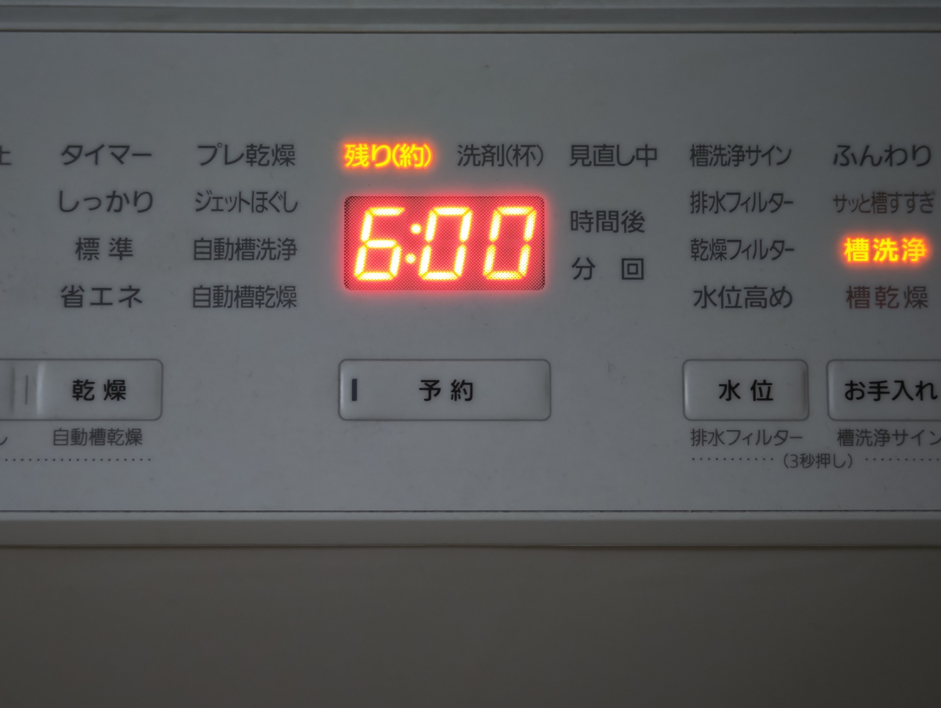 洗濯機の操作パネル。7セグメントに6:00と表示され、その上部に残り(約)が点灯している。下部には予約ボタンがある。